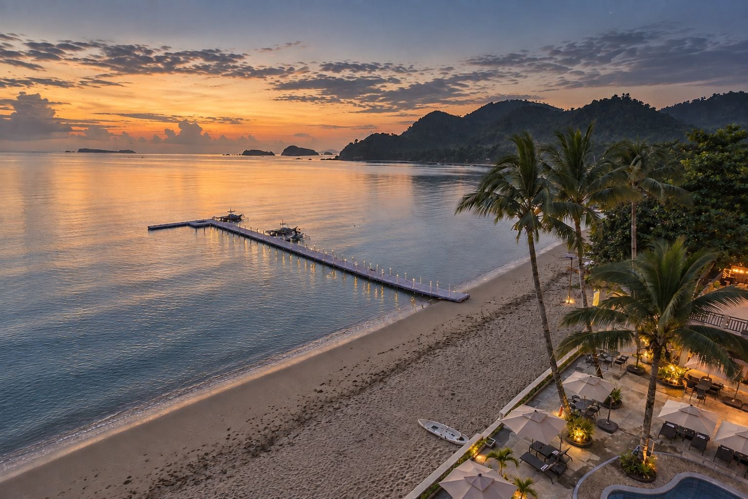 Una playa con un muelle que se adentra en el agua, palmeras y un área de piscina con sillones y sombrillas.