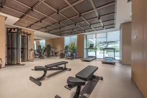 A gym with various exercise equipment, large windows, and a high ceiling. - StayShort - Elegant 1 Bedroom in JVC that Sleeps 2 (JVC)