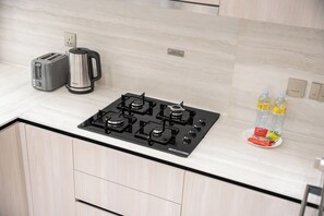 A kitchen with a Bosch gas stove, a toaster, a coffee maker, and a water dispenser. - StayShort - Elegant 1 Bedroom in JVC that Sleeps 2 (JVC)