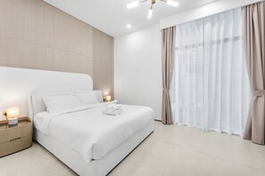 A modern hotel room with a large bed, bedside lamps, and sheer curtains. - StayShort - Elegant 1 Bedroom in JVC that Sleeps 2 (JVC)