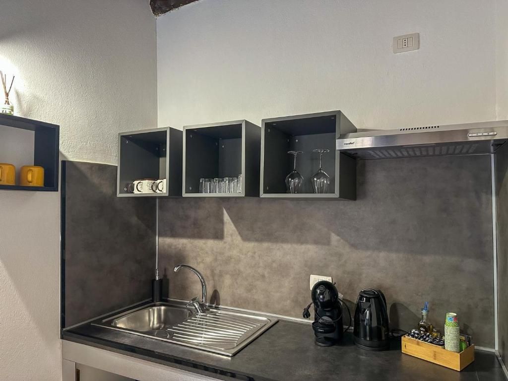 A modern kitchen with a stainless steel sink, black cabinets, and a coffee machine.