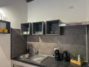 Una cocina moderna con un lavamanos de acero inoxidable, gabinetes negros y una cafetera.
