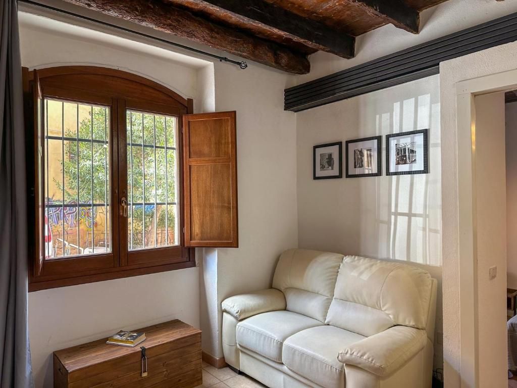A room with a wooden bench, a white sofa, and a window with a wooden shutter.
