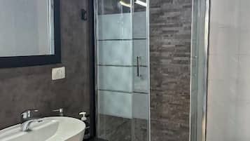 A modern bathroom with a glass-enclosed shower, a white sink, and a toilet.