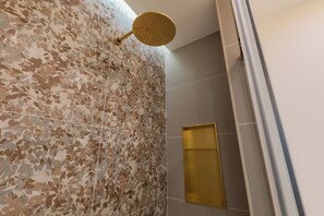 A bathroom with a shower area, a wall with a leaf pattern tile, and a gold-colored showerhead. - San Francesco Boutique House by Wonderful Italy. (Torino)