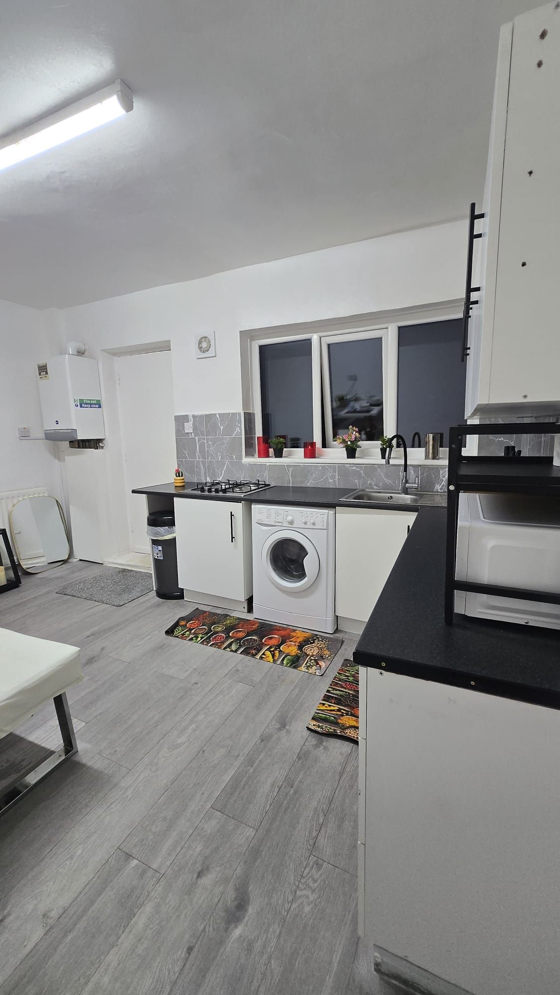 Une petite cuisine équipée d’un lave-linge, d’un évier et d’une fenêtre située au-dessus du plan de travail.