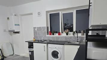 Une petite cuisine équipée d’un lave-linge, d’un évier et d’une fenêtre située au-dessus du plan de travail.