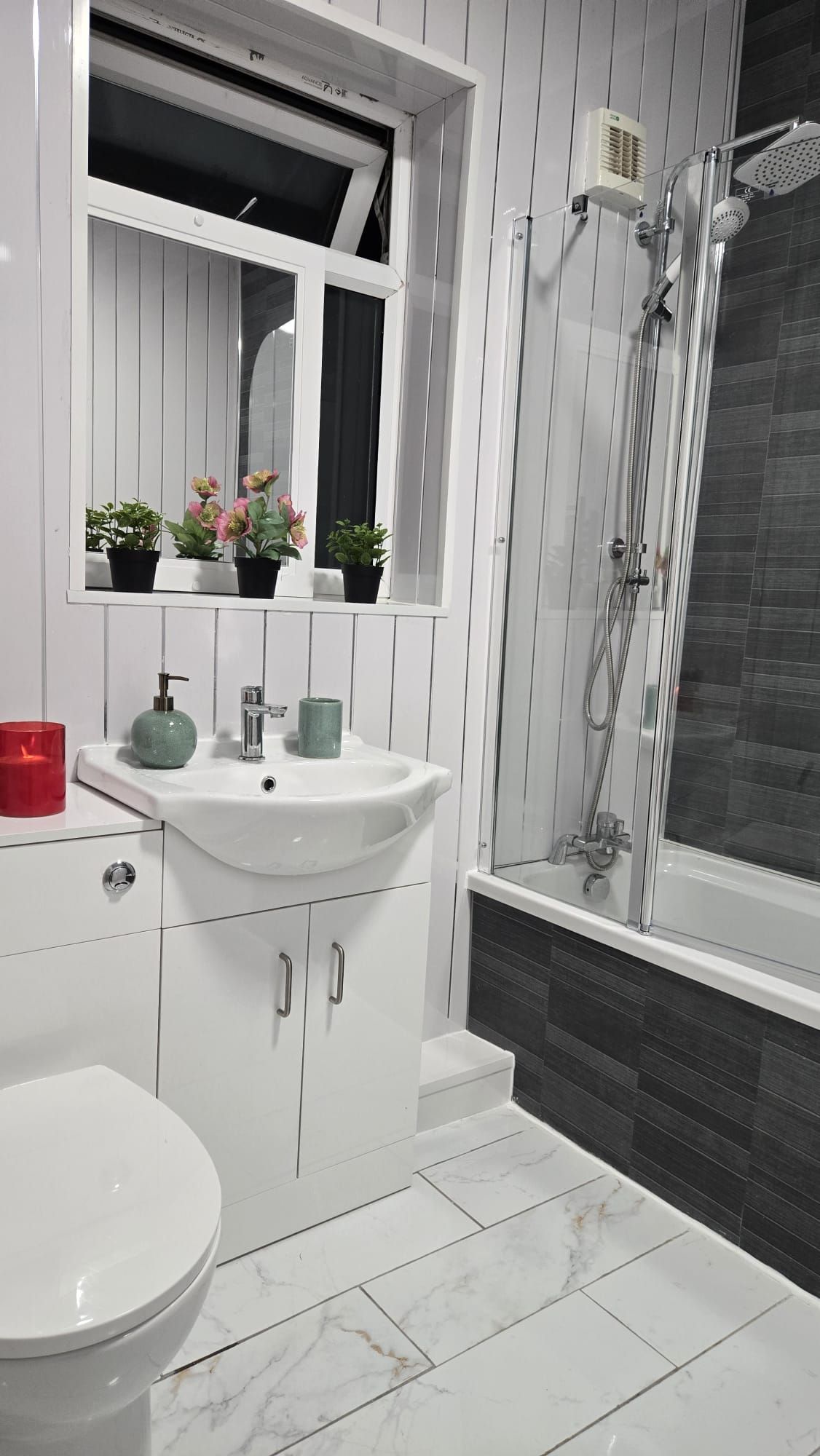 A bathroom with a white sink, a toilet, a shower, and a mirror above the sink.