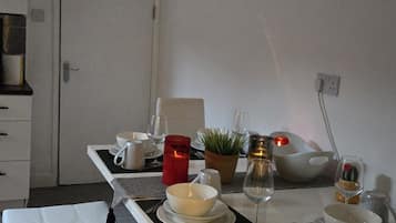 A dining area with a bench, a table set for two with plates, glasses, and a candle.