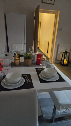 A dining table set with plates, cutlery, and glasses, with a potted plant and candles on the table. - Premium Newcastle Stay – Kingsley Terrace (Newcastle upon Tyne)