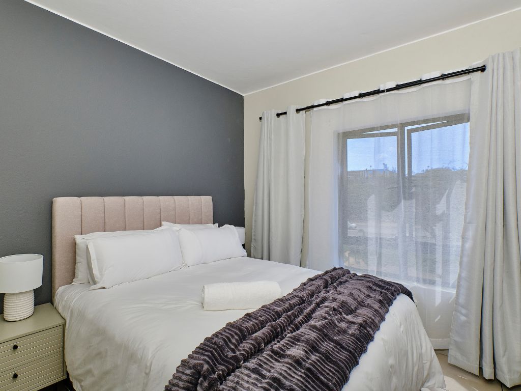 Un dormitorio con una cama, una mesita de noche y una ventana con cortinas.