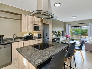 Une cuisine moderne dotée d’un îlot central, d’appareils électroménagers intégrés et d’un coin repas offrant une vue agréable.