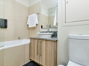 A bathroom with a bathtub, a sink, and a toilet. - Regentis Executive Stays at The Atrium Unit 163 (Johannesburg)