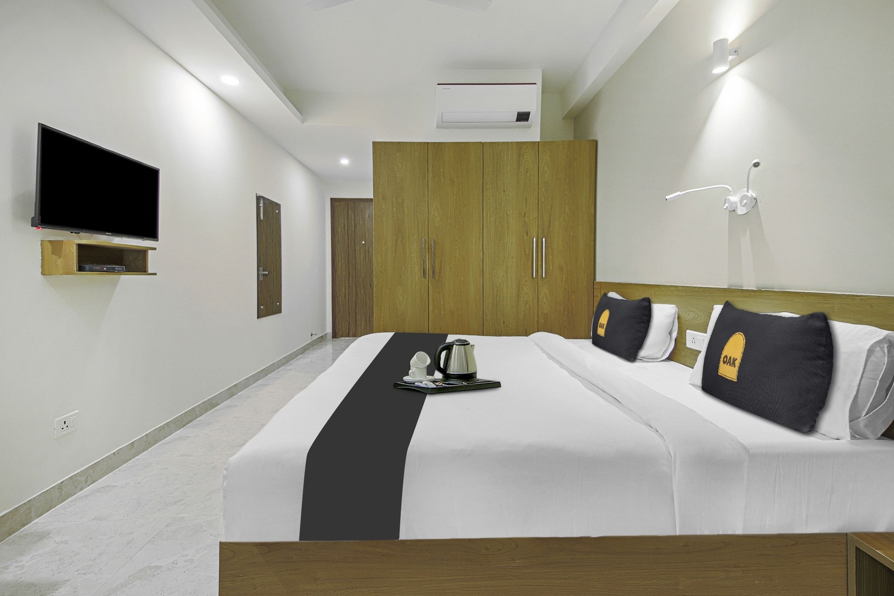 A hotel room with a bed, a TV, a wardrobe, and a wall-mounted air conditioner.