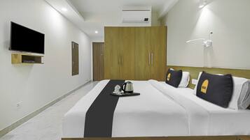 A hotel room with a bed, a TV, a wardrobe, and a wall-mounted air conditioner.