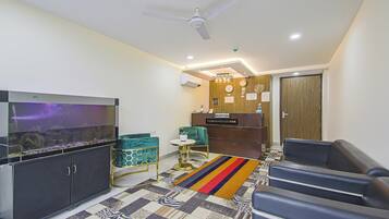 Een moderne woonkamer met een flatscreen televisie, een plafondventilator, een receptiebalie en een vloerkleed met een patroon.