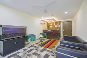 Ein modernes Wohnzimmer mit Flachbildfernseher, Deckenventilator, einer Rezeption und einem gemusterten Teppich.