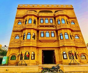 Ein mehrstöckiges Gebäude mit aufwendigen architektonischen Details, einem zentralen Eingang und einem Motorrad davor.