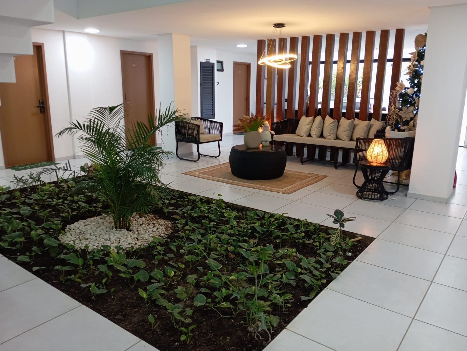 Un interior moderno con una zona de estar, un arreglo de plantas decorativo y una pared con listones de madera verticales.