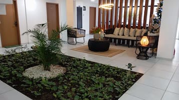 Un interior moderno con una zona de estar, un arreglo de plantas decorativo y una pared con listones de madera verticales.