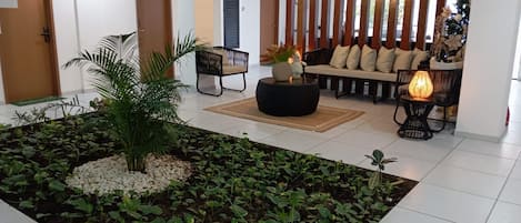 Un interior moderno con una zona de estar, un arreglo de plantas decorativo y una pared con listones de madera verticales.