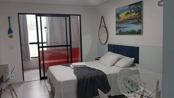 A bedroom with a bed, a chair, a window with curtains, and a painting on the wall.