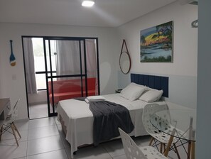 A bedroom with a bed, a chair, a window with curtains, and a painting on the wall. - Varandas do Porto (Ipojuca)
