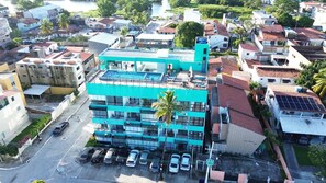 A multi-story building with a rooftop pool, surrounded by residential buildings and parked cars. - Varandas do Porto (Ipojuca)