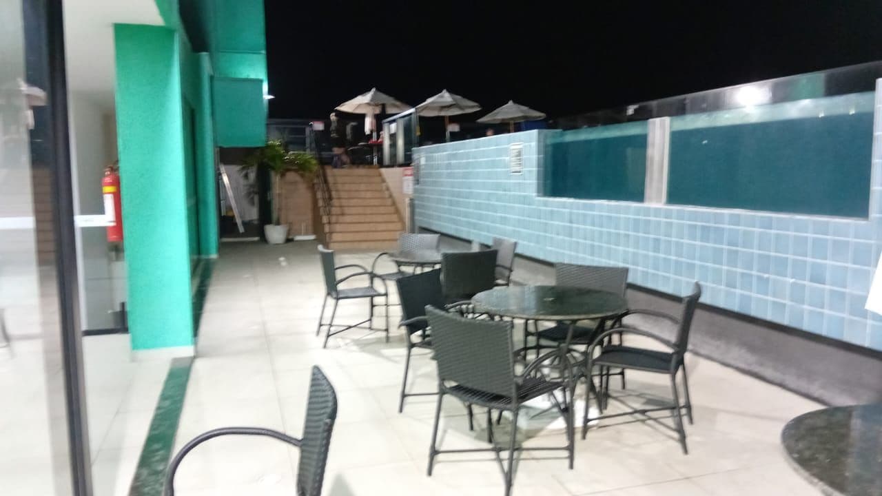 An outdoor seating area with tables and chairs, a tiled wall, and a staircase leading to an upper level.