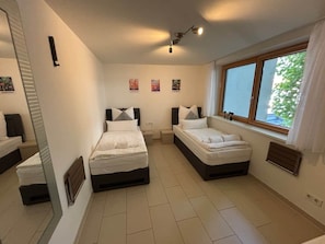 A bedroom with two beds, a window with curtains, and a mirror. - LakeView Deluxe - Best Lake View (Friedrichshafen)