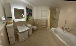 A modern bathroom with a bathtub, a toilet, a sink, and a vanity. - LakeView Deluxe - Best Lake View (Friedrichshafen)