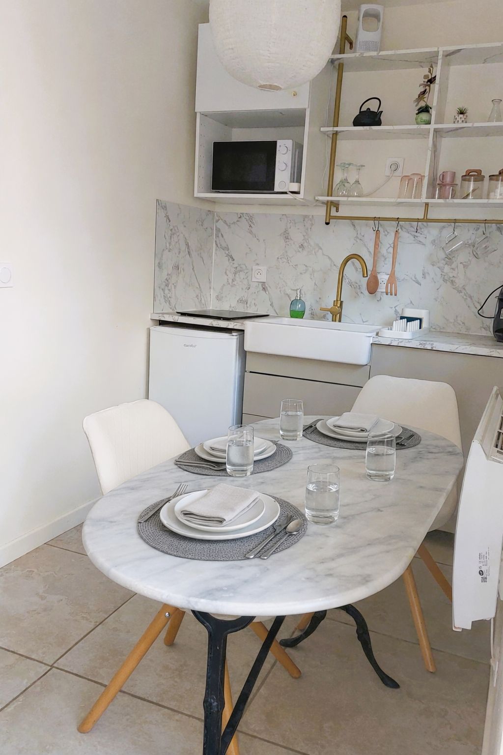 Une cuisine moderne dotée d’un plan de travail en marbre, d’un four à micro-ondes encastré et d’un évier avec un robinet doré.