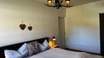 A bedroom with a large bed, a wall-mounted lamp, and a ceiling light fixture.