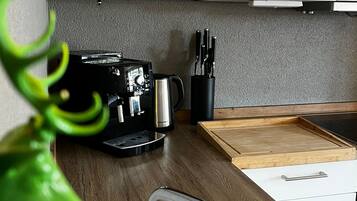 A compact kitchen with a coffee machine, a kettle, and a knife block.
