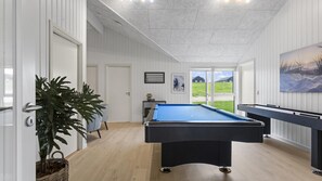 A pool table in a room with wooden flooring, white walls, and a door leading outside. - VillaVilla 1025 - Skåstrup Strand, Fyn og øer (Bogense)
