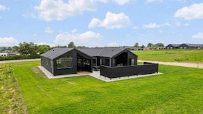 A modern black house with a large open patio, surrounded by a grassy field and a clear sky. - VillaVilla 1025 - Skåstrup Strand, Fyn og øer (Bogense)