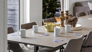 A dining table with white mugs, a yellow teapot, and playing cards. - VillaVilla 1025 - Skåstrup Strand, Fyn og øer (Bogense)