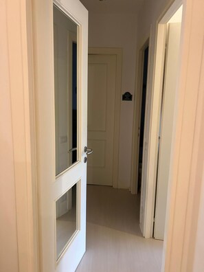 Ein Flur mit einer zur einem Zimmer führenden Tür, einer Tür mit einem Schild und einer Tür mit einem Griff.