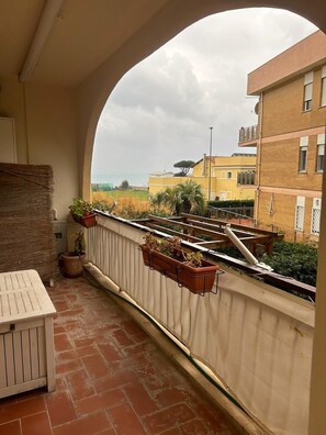 Ein Balkon mit Blick auf das Meer, mit Terrakottafliesen, einem weißen Tisch und Topfpflanzen.