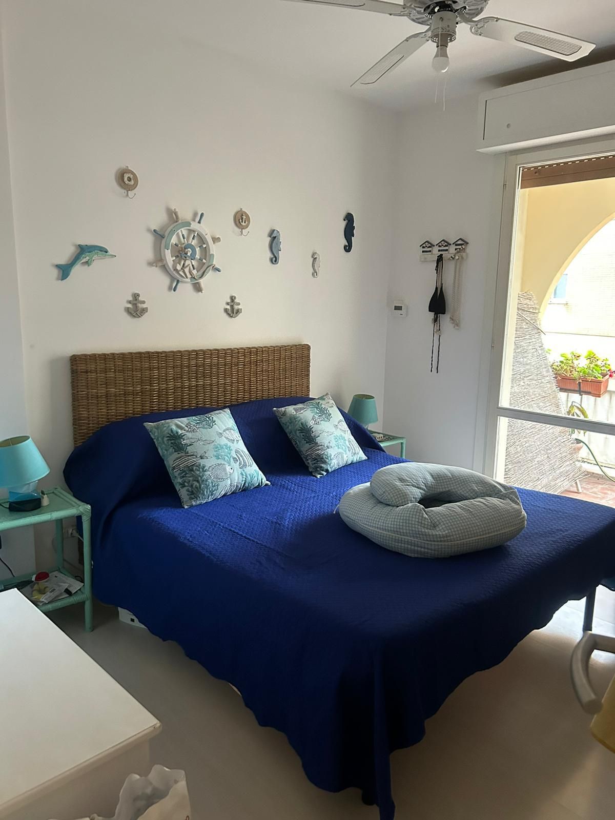 Una camera da letto con un letto, una ventola a soffitto e decorazioni a tema nautico.