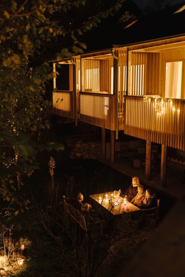 A wooden cabin with a fire pit and string lights.