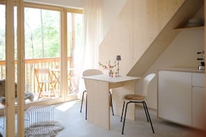 A room with a wooden table and chairs, a small cabinet, and a view of the outdoors. - Tiny Lodge Bad Ischl, Salzkammergut #2 (Bad Ischl)