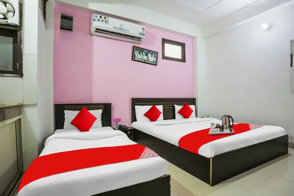 A hotel room with two beds, a pink wall, and an air conditioning unit. - Capital O Ram Krishna residency (Gurugram)