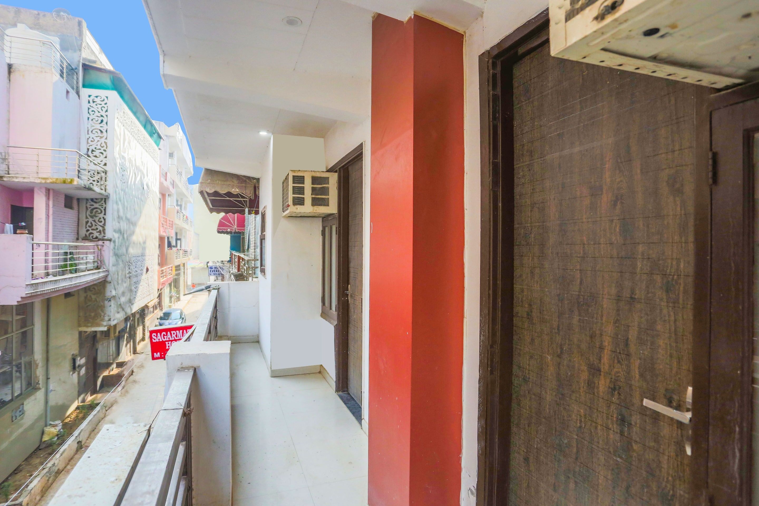 A narrow corridor with a red pillar, a wooden door, and a sign for a hotel.