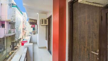 A narrow corridor with a red pillar, a wooden door, and a sign for a hotel.
