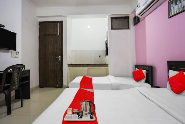 A hotel room with two beds, a desk, a television, and a bathroom visible through an open door. - Capital O Ram Krishna residency (Gurugram)