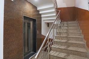 A staircase with a metal railing, a door, and a wall with a brown and white pattern. - Capital O Ram Krishna residency (Gurugram)