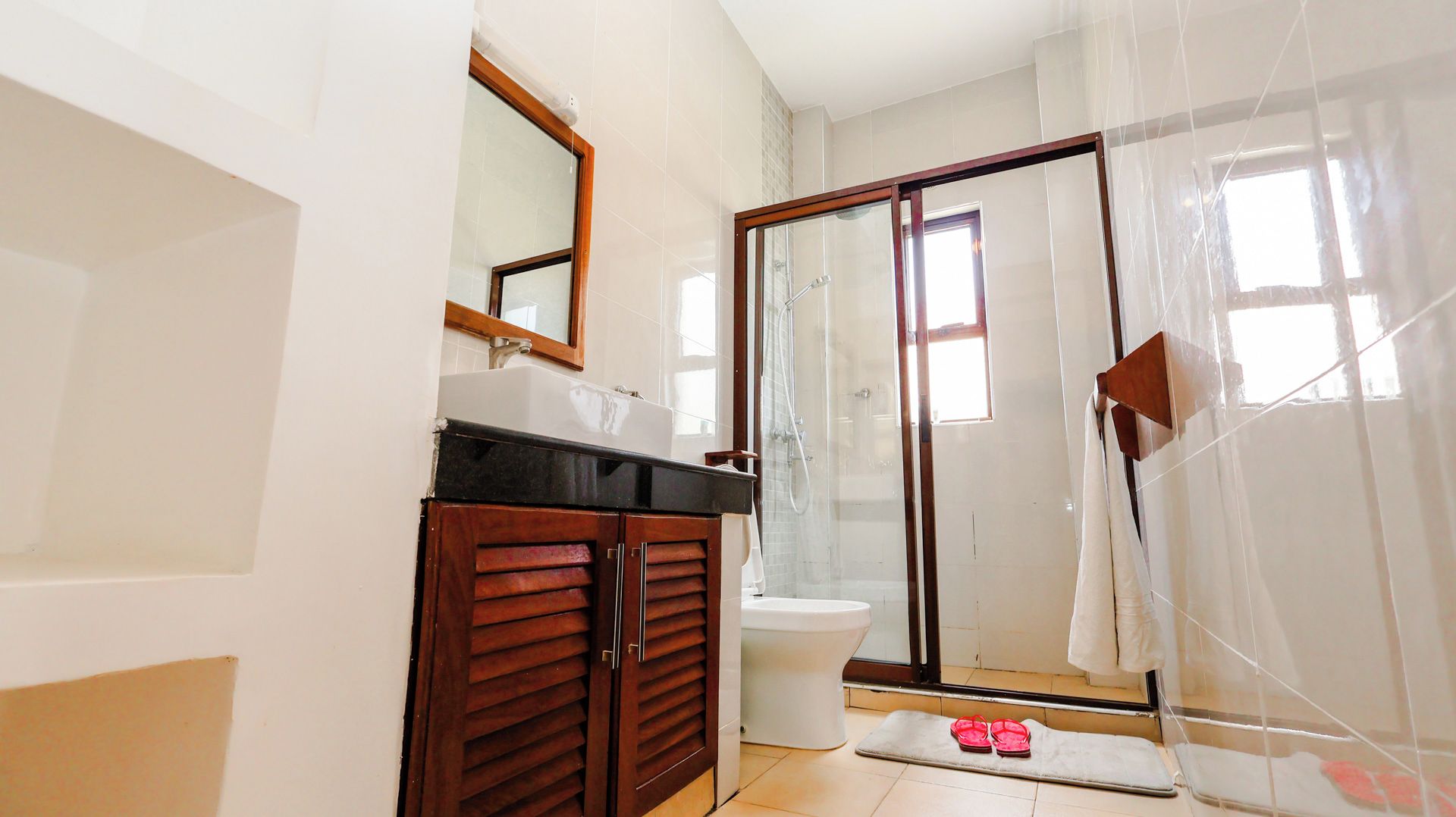 Un baño con ducha, inodoro y tocador con espejo.