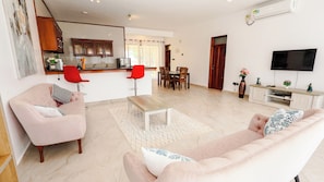 Uma sala de estar moderna com sofá, poltronas, mesa de centro e televisão.