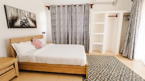 Quarto com cama de madeira, mesa de cabeceira, tapete estampado e guarda-roupa.
